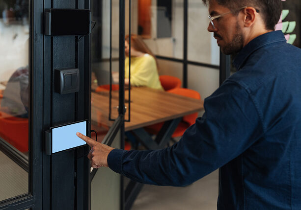 Man using touchscreen device at office entrance